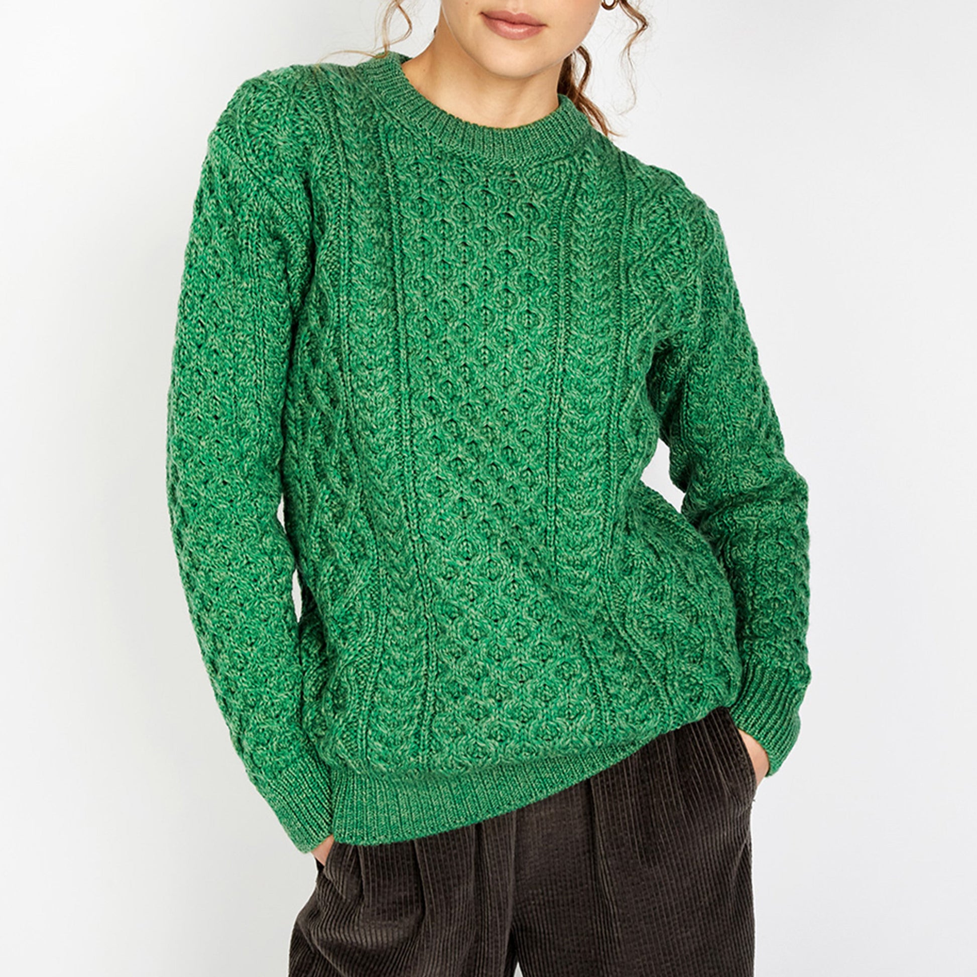 Person wearing a green cable knit sweater against a white background