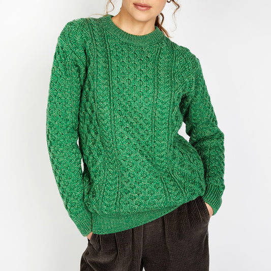 Person wearing a green cable knit sweater against a white background